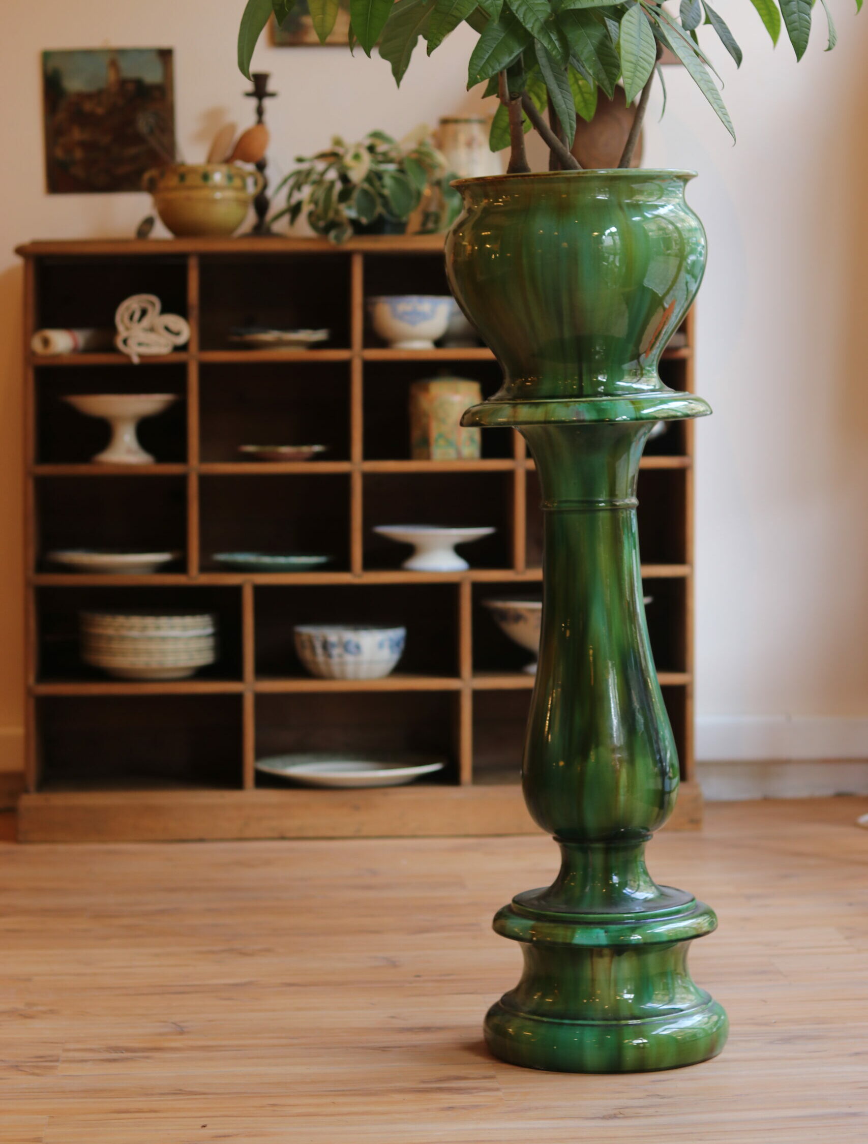 Beau meuble de rangement à casiers en pin massif, datant du début du XXᵉ siècle. Composé de 18 compartiments (12 petits et 6 grands), il offre une capacité de rangement généreuse et décorative, idéale pour une vaisselle ancienne, des livres ou des objets de collection. Finition cirée, plateau supérieur à bords arrondis et base soulignée d’une élégante plinthe moulurée. Dimensions : hauteur 100 cm – longueur 115 cm – profondeur 32 cm. En bon état général, avec quelques traces anciennes d’usage dans deux casiers (taches d’huile ou de gras). Colonne jardinière Art Nouveau en faïence émaillée flammée vert, Sarreguemines, vers 1900